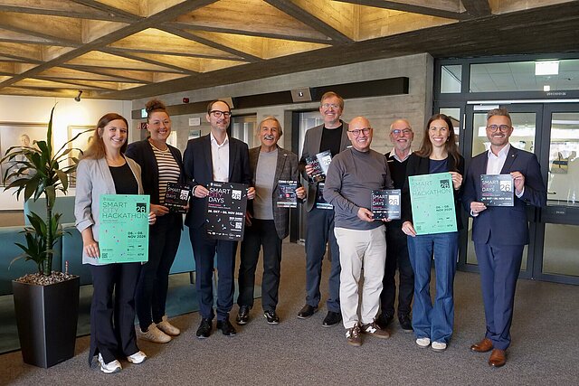 Eine Gruppe von Personen steht zusammen, alle halten Plakate oder Broschüren in den Händen.