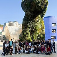 Ein Gruppe Menschen vor einer begrünten Skulptur.