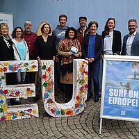 Viele Personen stehen aufgereiht hinter großen Buchstaben, die das Wort EU bilden