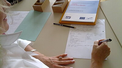 Frau am Tisch macht sich Notizen