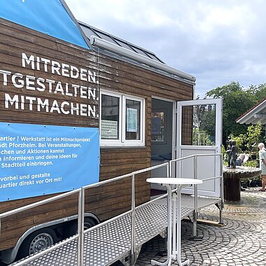 Ein holzverkleidetes Tiny House steht auf einem Platz.