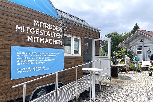 Ein holzverkleidetes Tiny House steht auf einem Platz.