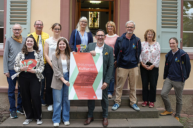 Elf Personen, die sich am Programm des Brötzinger Kulturfestes beteiligen, stehen vor dem Stadtmuseum Brötzingen. In der Mitte steht Kulturbürgermeister Tobias Volle und hält das Plakat zum Brötzinger Kulturfest vom 25. bis 27. September 2026, eine Frau links mehrere Programmflyer. 