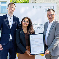 Maximilian Motz, Yusrea Valiyakath und WSP-Direktor Oliver Reitz präsentieren bei der Förderpreisverleihung der Hochschule Pforzheim die Auszeichnung für die Studie zur Busanbindung.