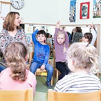 Kinder sitzen im Stuhlkreis
