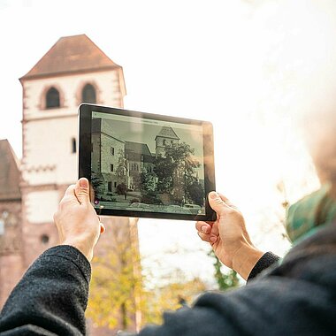 Future History App Person mit Tablet, draußen in Pforzheim, benutzt die Future History App
