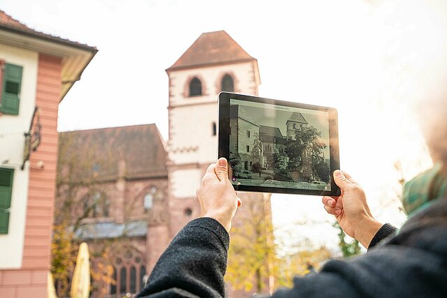Person mit Tablet, draußen in Pforzheim, benutzt die Future History App