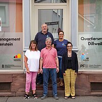 Fünf Personen stehen vor einem Gebäude, mit der Aufschrift "Quartiersmanagement Dillweißenstein"
