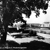 Schwarz-Weiß-Foto: Der Davosweg an der Nagold im Jahr 1931. Im Hintergrund ist die Kallhardtbrücke (damals noch Hindenburgbrücke) zu sehen. - copyright:Stadtarchiv Pforzheim – Institut für Stadtgeschichte, S1-8-Davosweg-R-3