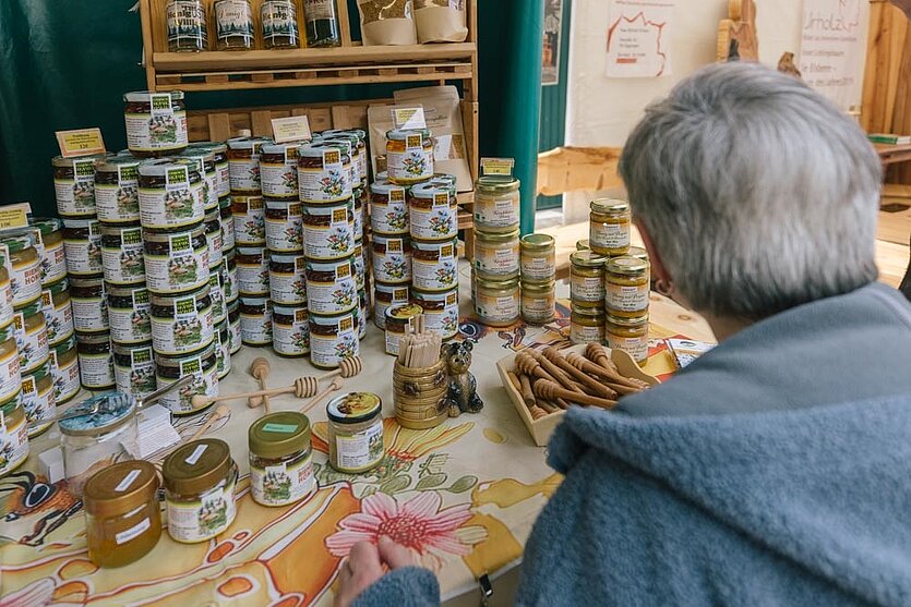 Eine Frau steht an einem Honig-Verkaufsstand und betrachtet die Auslage. - copyright: Naturpark-Markt Schwarzwald Mitte/Nord - Ersteller: Johannes Nickel