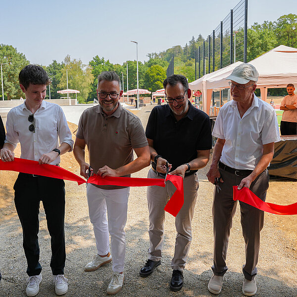 Oberbürgermeister Peter Boch (Dritter von links), Bürgermeister Frank Fillbrunn (Zweiter von rechts) sowie Bürgermeister Tobias Volle (Dritter von rechts) und der Vorsitzende des Jugendgemeinderats, Leon Meyer (Zweiter von links), schneiden ein rotes Band durch und weihten die neue Sport- und Freizeitanlage im Enzauenpark mit weiteren Vertretern des Jugendgemeinderats ein. - Copyright: Stadt Pforzheim