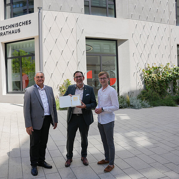 Ihab Mousa, Prokurist der Stuttgarter Niederlassung von Ten Brinke, Baubürgermeister Tobias Volle sowie Daniel Scheufler, Schlossberghöfe-Projektkoordinator der Stadt, präsentieren stolz das DGNB-Gold-Zertifikat vor der Fassade des neuen Technischen Rathauses. - Copyright: Stadt Pforzheim