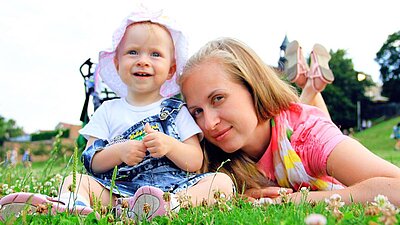 Mutter und Tochter liegen auf einer Wiese