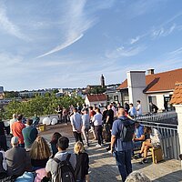 Viele Menschen auf einer sonnigen Dachterrasse