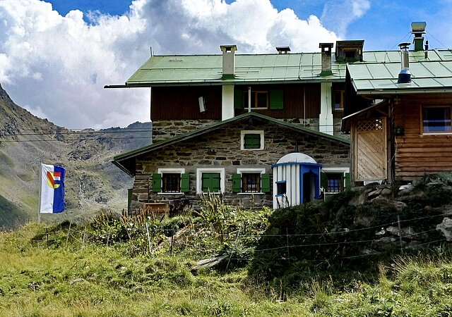 Auf dem Bild ist die Pforzheimer Hütte in den Tiroler Alpen zu sehen.