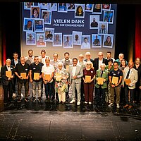Eine Gruppe von Personen stehen auf einer Bühne und halten Urkunden in den Händen.