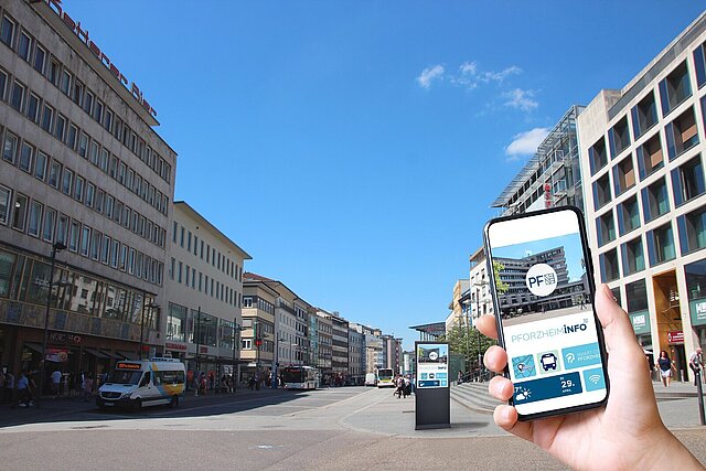 Eine Informationsstele und ein Handybildschirm mit einer Stadt-App in der Pforzheimer Innenstadt.