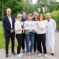 Gruppe, die ein Schild mit dem Logo des Demenznetzwerks hält