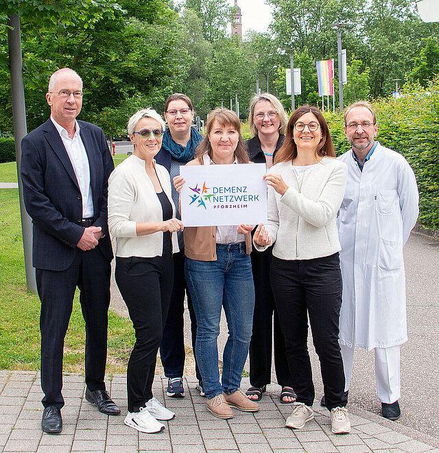 Gruppe, die ein Schild mit dem Logo des Demenznetzwerks hält