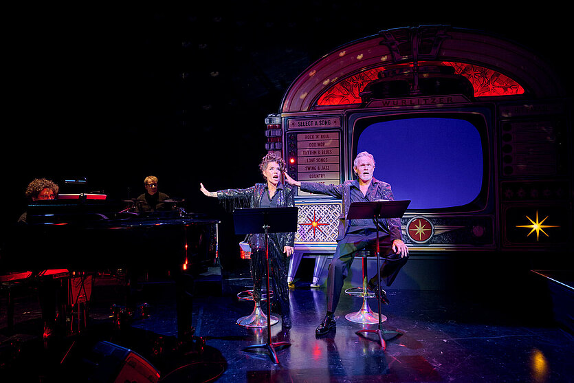 Lilian Huynen und Jon Goldsworthy sitzen im Bühnenbild - copyright: Theater Pforzheim - Ersteller: MARTIN SIGMUND