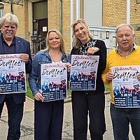 Vier Personen halten jeweils ein Plakat in die Höhe.