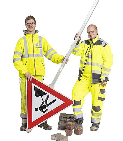 Azubis Straßenwärter der Stadt Pforzheim Foto: Zwei Auszubildende Straßenwärter in Arbeitskleidung und mit Straßenschild