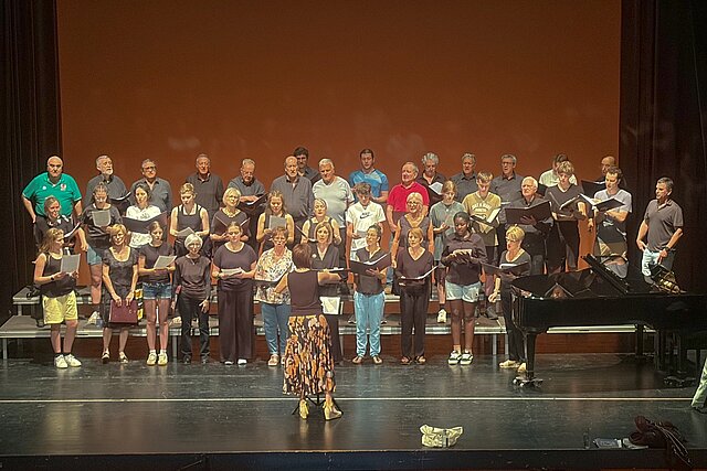 Viele Menschen auf einer Bühne, die singen. 