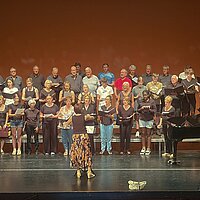 Viele Menschen auf einer Bühne, die singen.