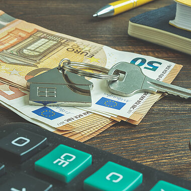 Euro und Schlüssel für die Wohnung als Symbol für Geld für Miete oder Kauf einer Immobilie.