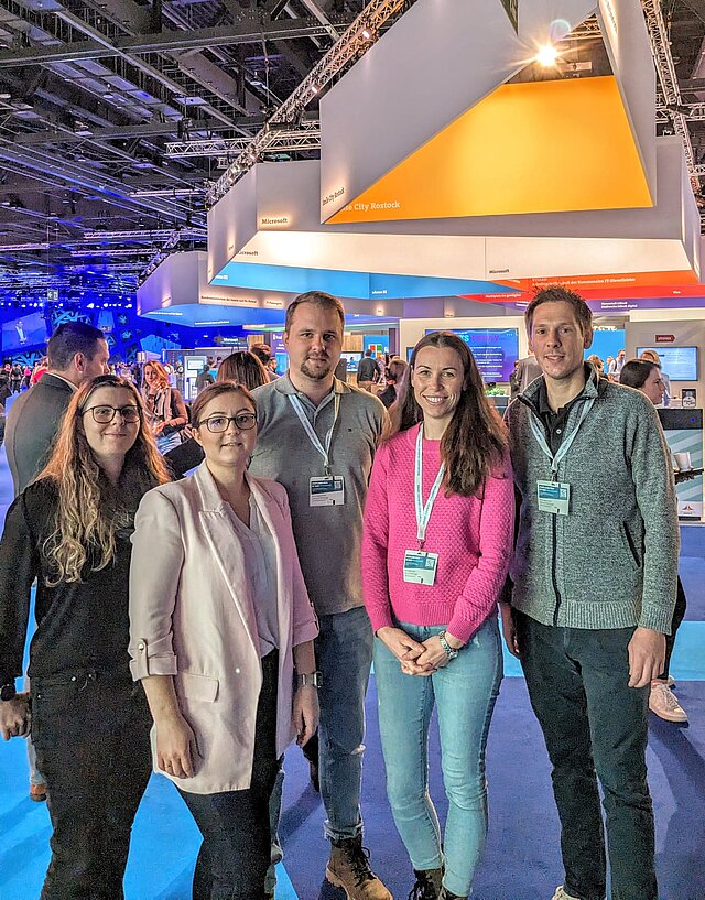 Teamfoto mit fünf Personen auf dem Messegelände
