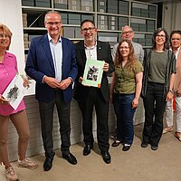 Sieben Personen stehen vor einem Archivregal des Stadtarchivs Pforzheim.