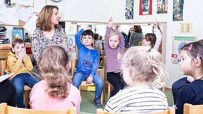 Kinder sitzen im Stuhlkreis