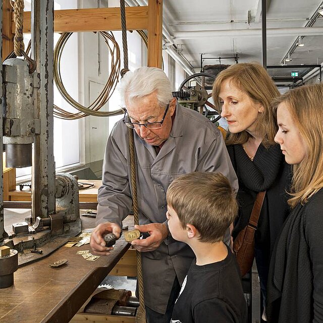 Mitarbeiter des Technischen Museums erklärt Besuchern den Fallhammer