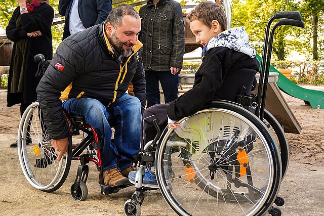 Kind und Mann im Rollstuhl spielen