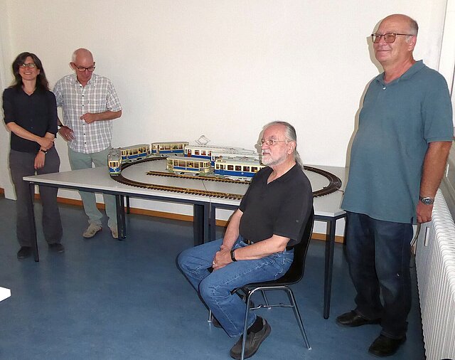 Archivleiterin Dr. Klara Deecke und der Obermeister der Löblichen Singergesellschaft Kai Adam freuen sich mit dem Referenten Kurt Schwab über die Modell-Straßenbahn von Andreas Simmel (v.l.n.r.) (Foto: Stadt Pforzheim, Schmidt)