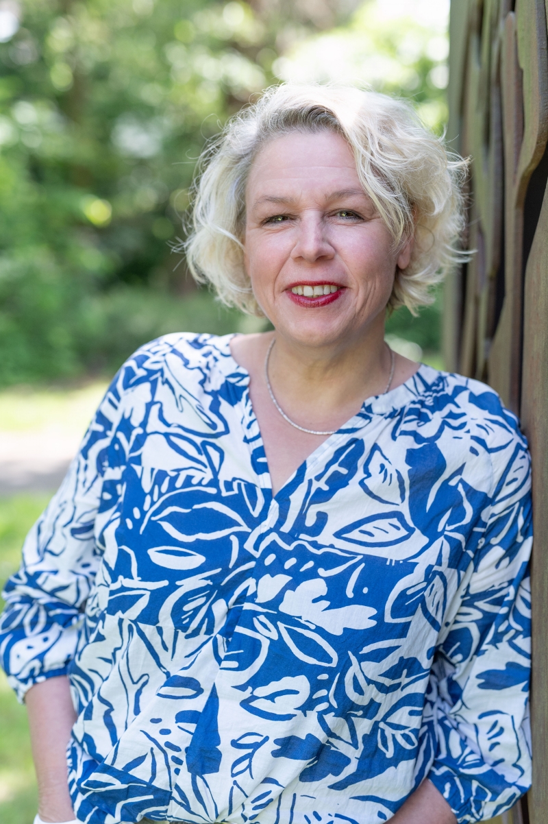 Fotografie einer Frau mit blonden Haaren und einer blau weißen Bluse in der Natur stehend. - copyright: Daniela Heiser - Ersteller: Daniela Heiser